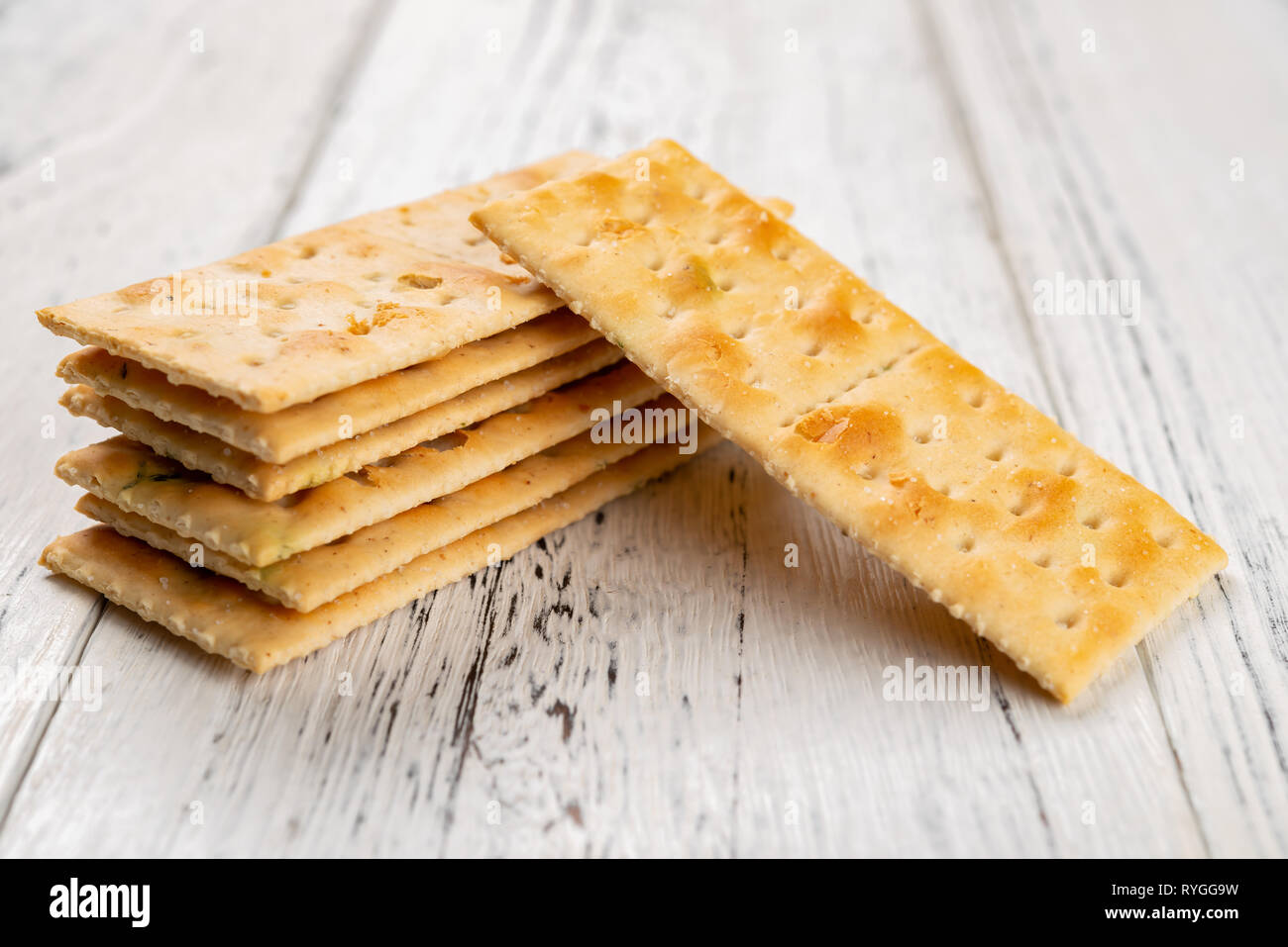 Knusprige Cracker bis auf weißem Holz Hintergrund gestapelt Stockfoto