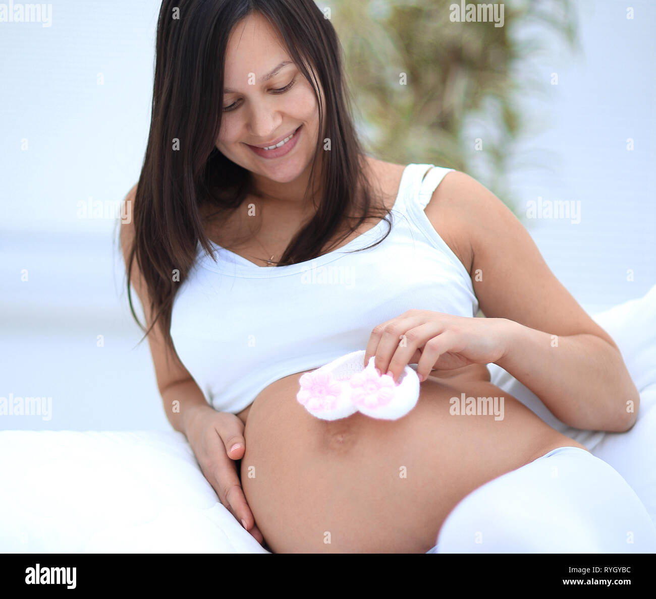 Schöne schwangere Frau im Wohnzimmer sitzen. Stockfoto