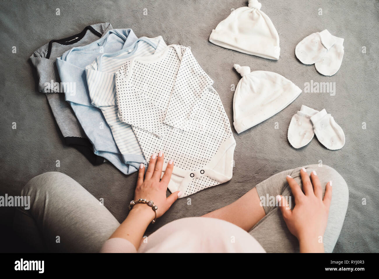 Schwangere unkenntlich Sitzende Frau mit Baby Kleidung. Ansicht von oben Stockfoto