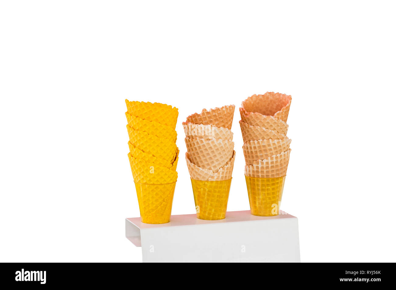 Eistüten von gebackenen Waffeln in der Form von Kegeln, die mit verschiedenen Farben in Plastikbecher auf Stativ auf einem weißen Hintergrund. Stockfoto