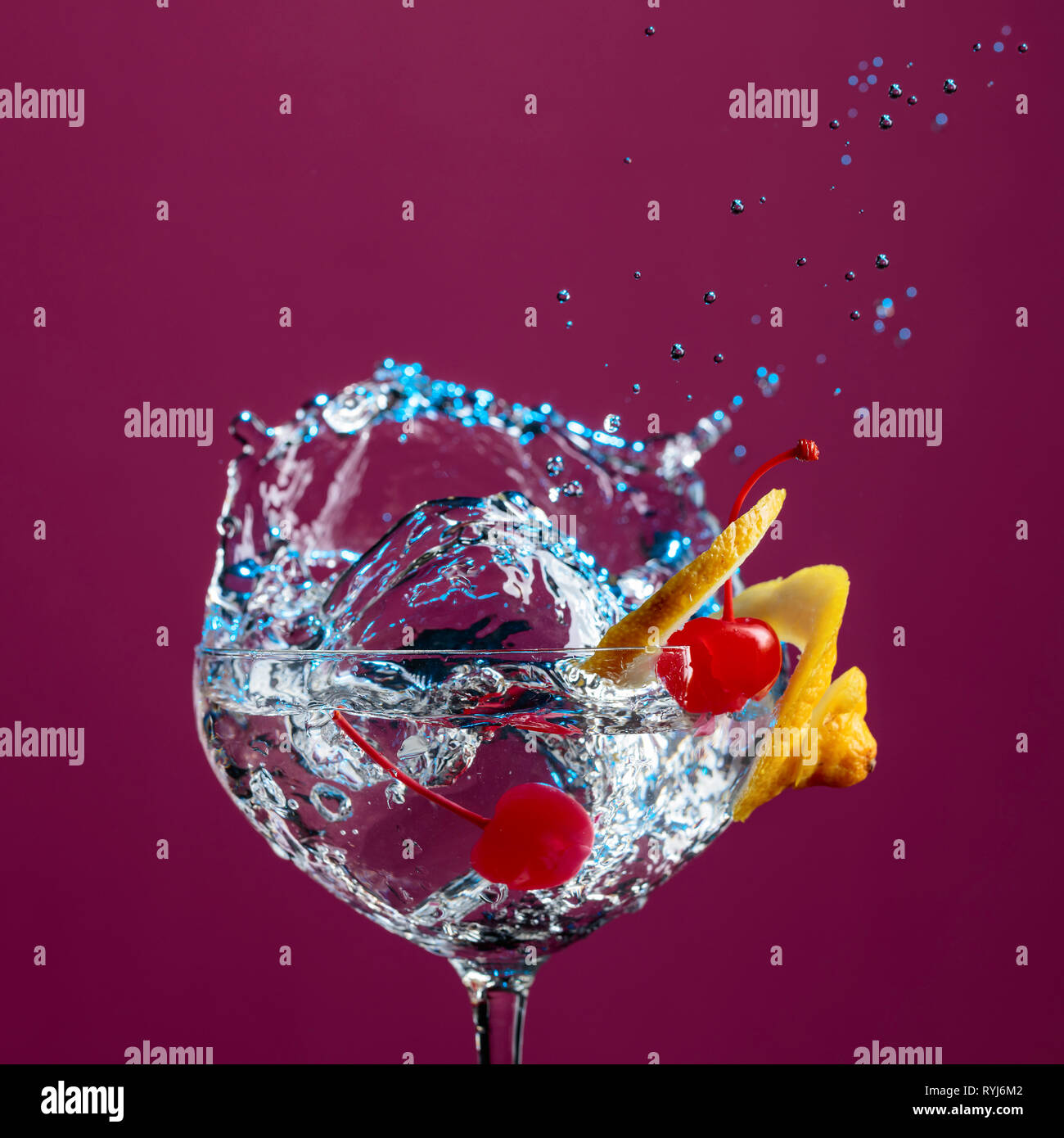 Cocktail in Glas mit Spritzern garniert mit Zitrone und Kirschen. Purple Background. Stockfoto