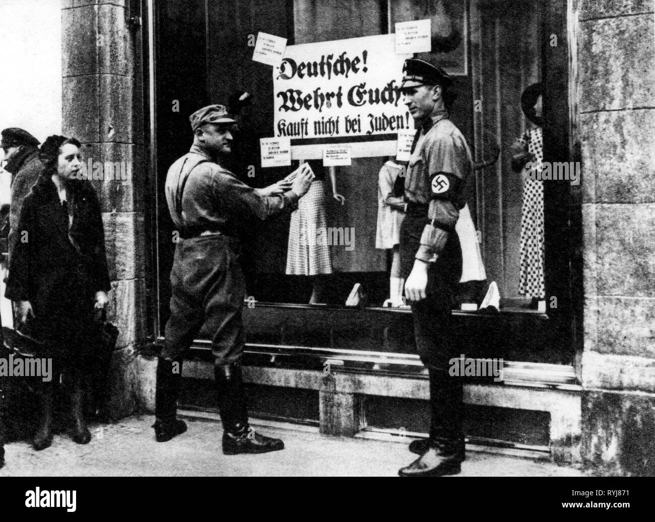 Nationalsozialismus / Nationalsozialismus, Verfolgung der Juden, Boykott jüdischer Geschäfte, Sturm Bataillon Mann und SS-Mann klemmt Boykott Poster auf Schaufenster, 'Deutsche! Wehrt Euch! Kauft nicht bei Juden!" Wahrscheinlich Berlin, Deutschland, 1.4.1933, Additional-Rights - Clearance-Info - Not-Available Stockfoto