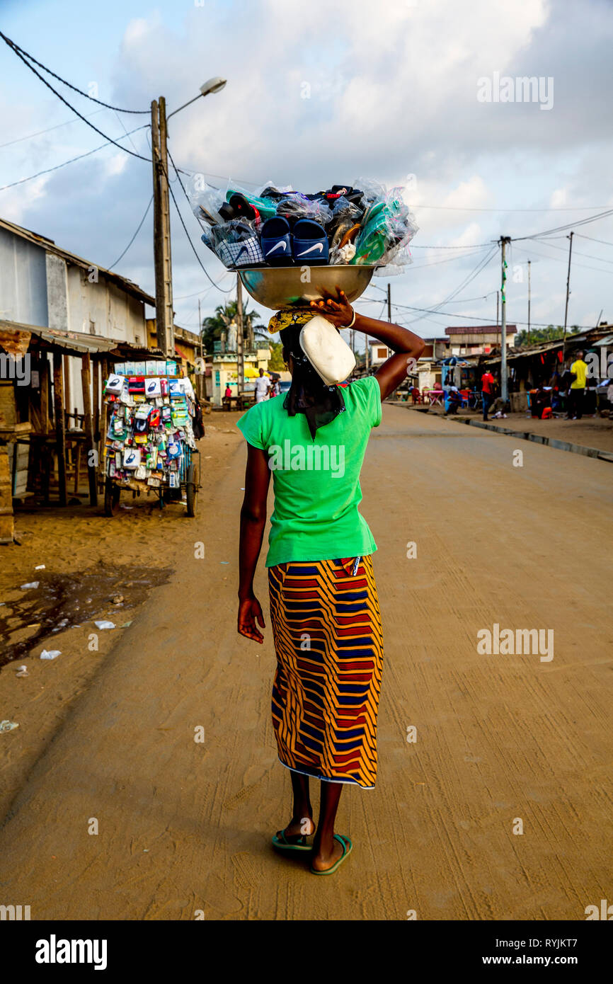 Frau Sandalen verkaufen ihre Ware, die ihr Kopf in Grand Bassam, Elfenbeinküste. Stockfoto