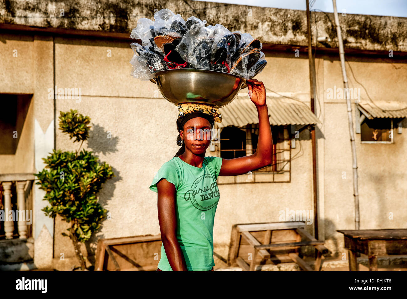 Frau Sandalen verkaufen ihre Ware, die ihr Kopf in Grand Bassam, Elfenbeinküste. Stockfoto