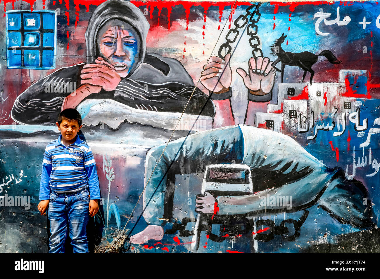 Palästinensischer Junge stand vor einer bemalten Wand in Dschenin, West Bank, Palästina. Stockfoto