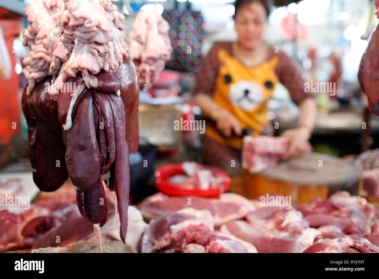 Fleischstücke hängen an Haken an einem traditionellen Markt Metzgerei. Ha Tien. Vietnam. Stockfoto