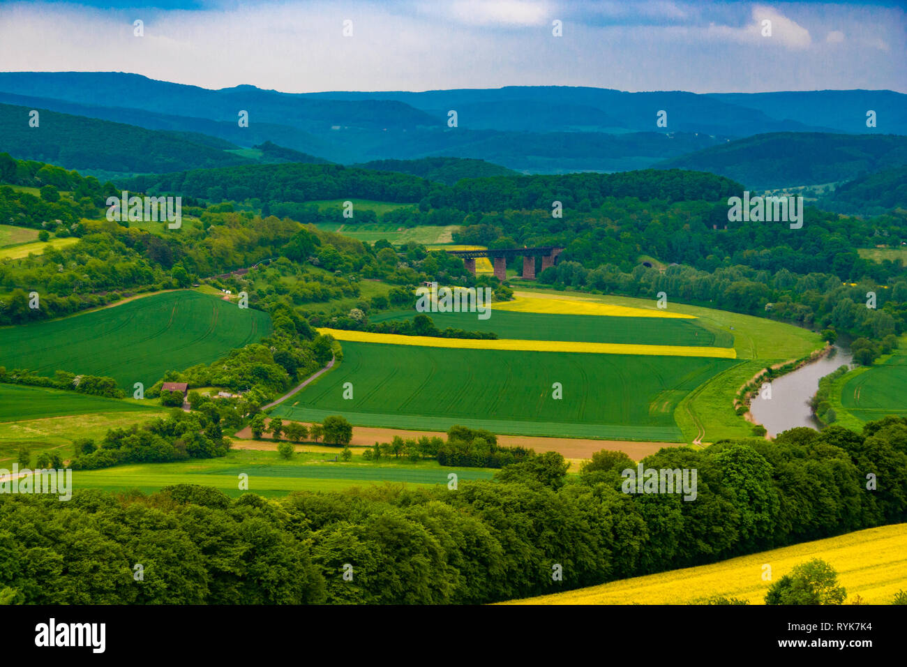 Schöne Panoramasicht auf das Werratal Landschaft. Die Werra fließt durch angebaute Raps Felder und eine Eisenbahnbrücke, umgeben von Wald... Stockfoto