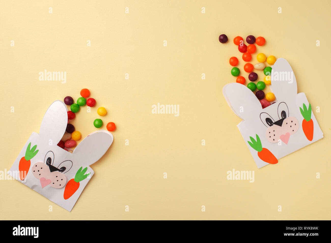 Ostern bunte Bonbons und Fruchtgummi, die sich aus Partei Papier Handwerk Tasche auf Gelb weißen Hintergrund. Osterhasen Package. Kopieren Sie Raum, Flach, Hap Stockfoto