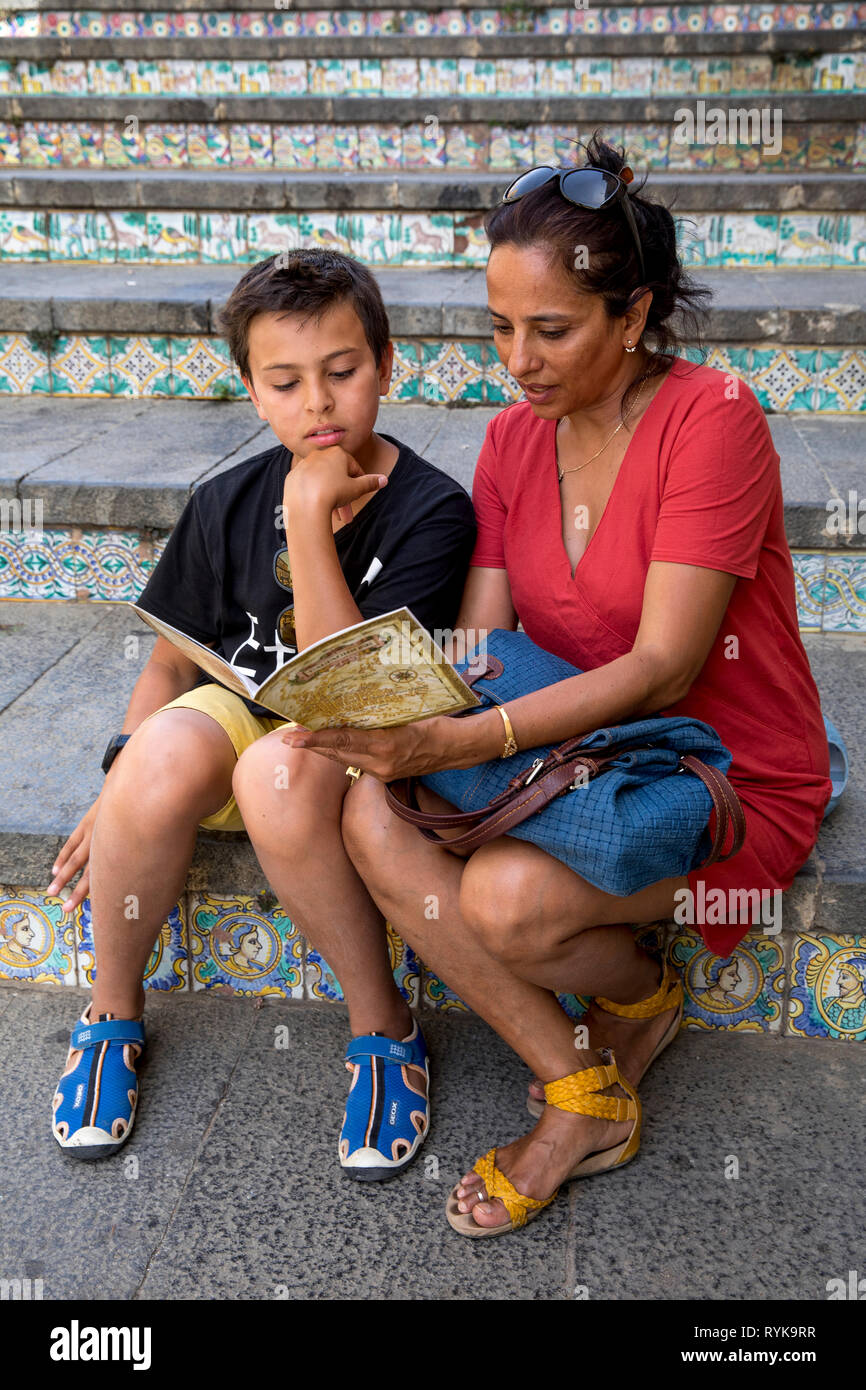 Mutter und Sohn Lesung einen Reiseführer über eine Treppe in Caltagirone, Sizilien (Italien). Stockfoto
