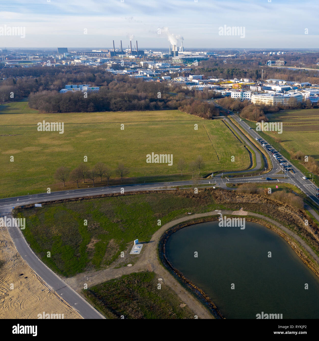 Luftaufnahme von Regenwasser Rückhaltebecken mit Straßen und eine große Wiese und eine industrielle Stadt im Hintergrund. Stockfoto