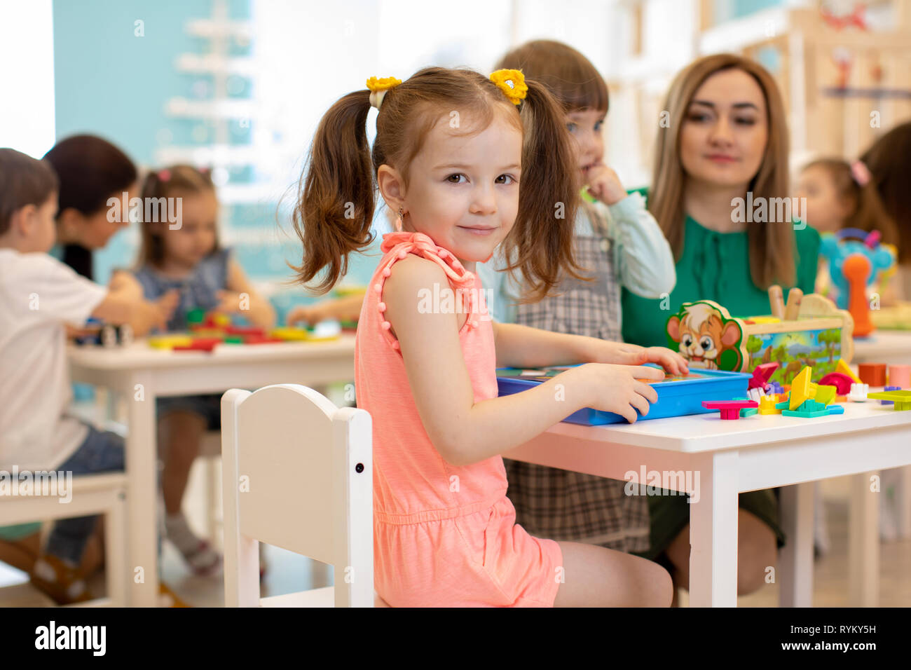 Lehrer spielt mit Kindern im Kindergarten oder in der Kindertagesstätte