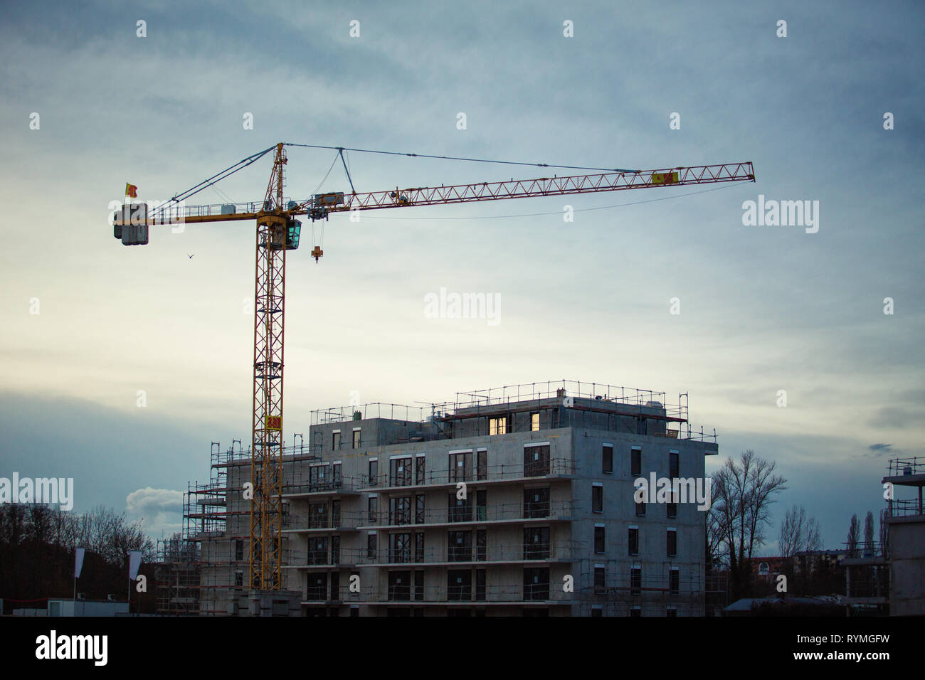 Baustelle Hintergrund und arbeiten Turm Kran über eine konkrete Gebäude mit Gerüst Elementen und Details im Abendlicht. Stockfoto