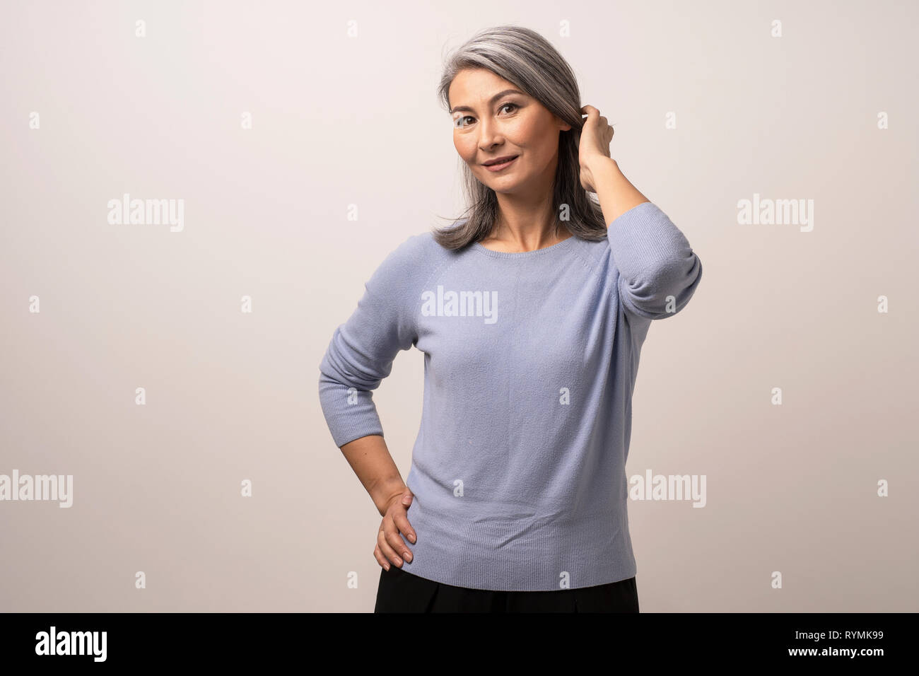 Lächelnd asiatische Frau berührt ihr graues Haar Stockfoto