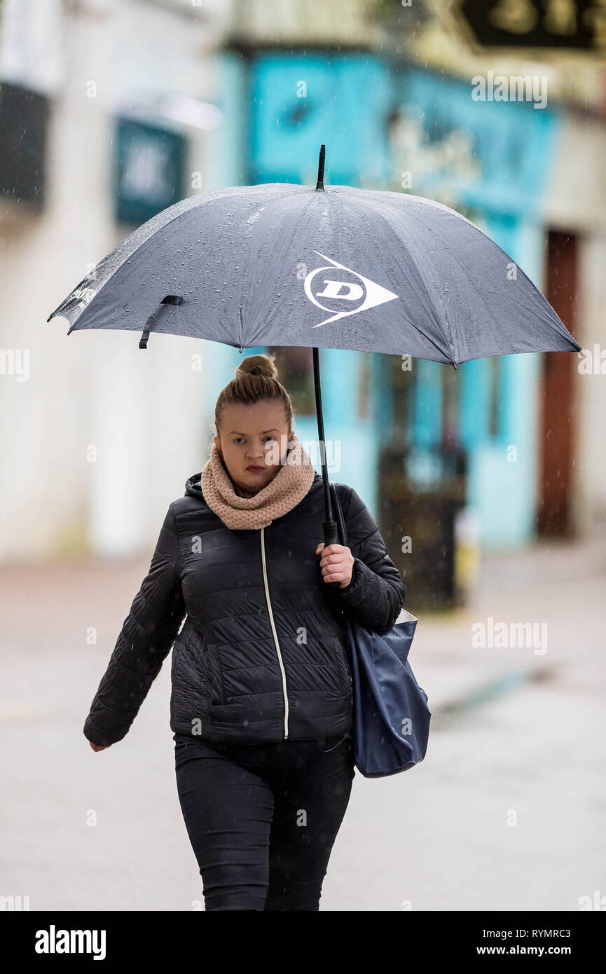 Dienstag, 12. März 2019 Im Bild: eine Frau versteckt unter ihrem Dach in Carmarthen, Wales UK vor Sturm Gareth Re: Starke Winde Reisen gebracht haben Stockfoto