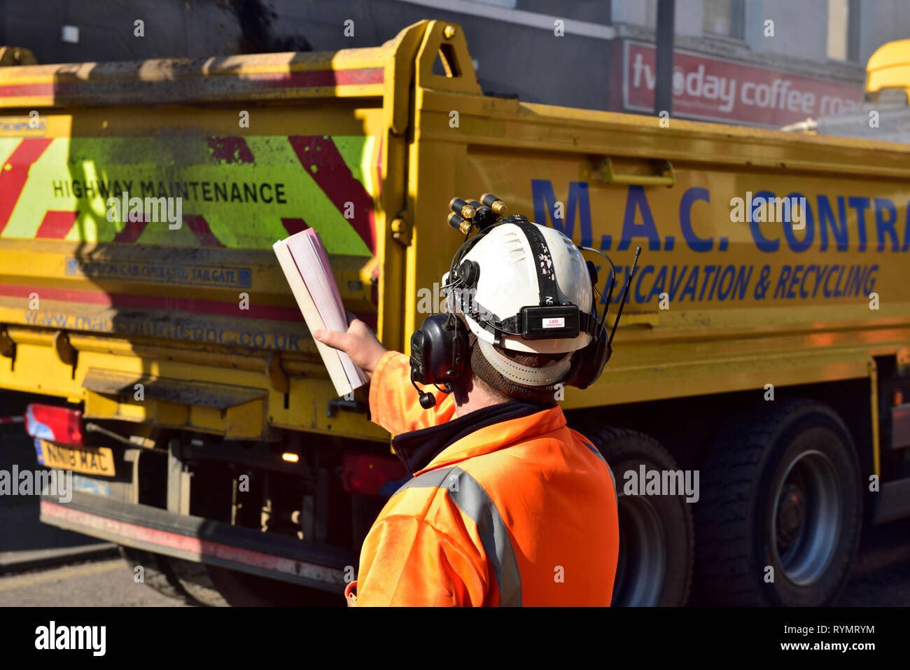 Bauarbeiter leitet Kipper Lkw als, die es sichert seine Last zu fallen Stockfoto