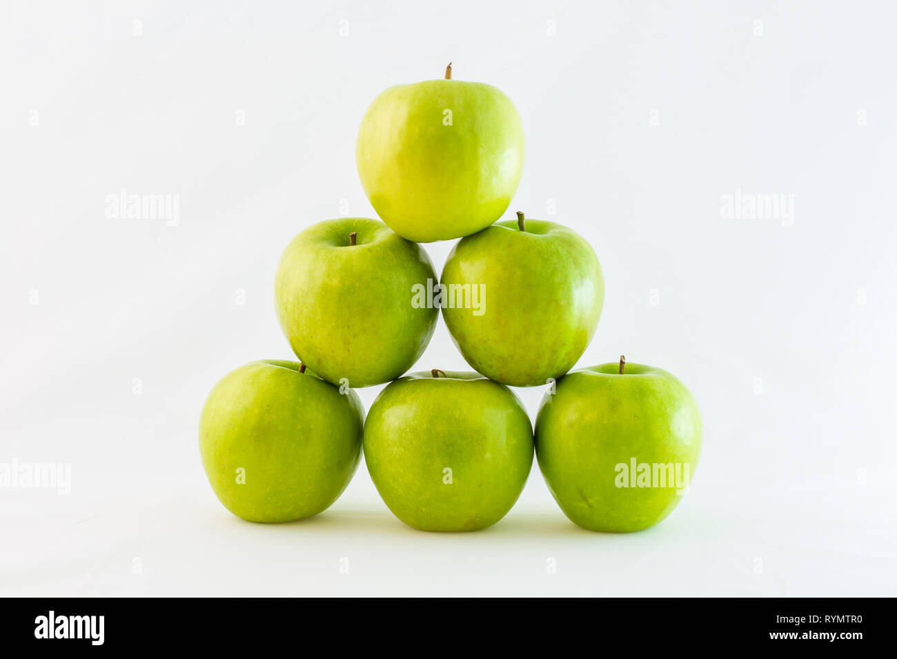Grüne Granny Smith Äpfel in einem Dreieck oder Pyramide gestapelt, auf weißem Hintergrund. Stockfoto