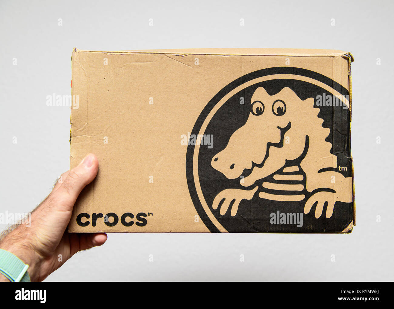 Paris, Frankreich, 12.Juni 2018: der Mensch Hand hält frisch geliefert Crocs schuhe Karton mit großen Krokodil Logo mit weißem Hintergrund Stockfoto