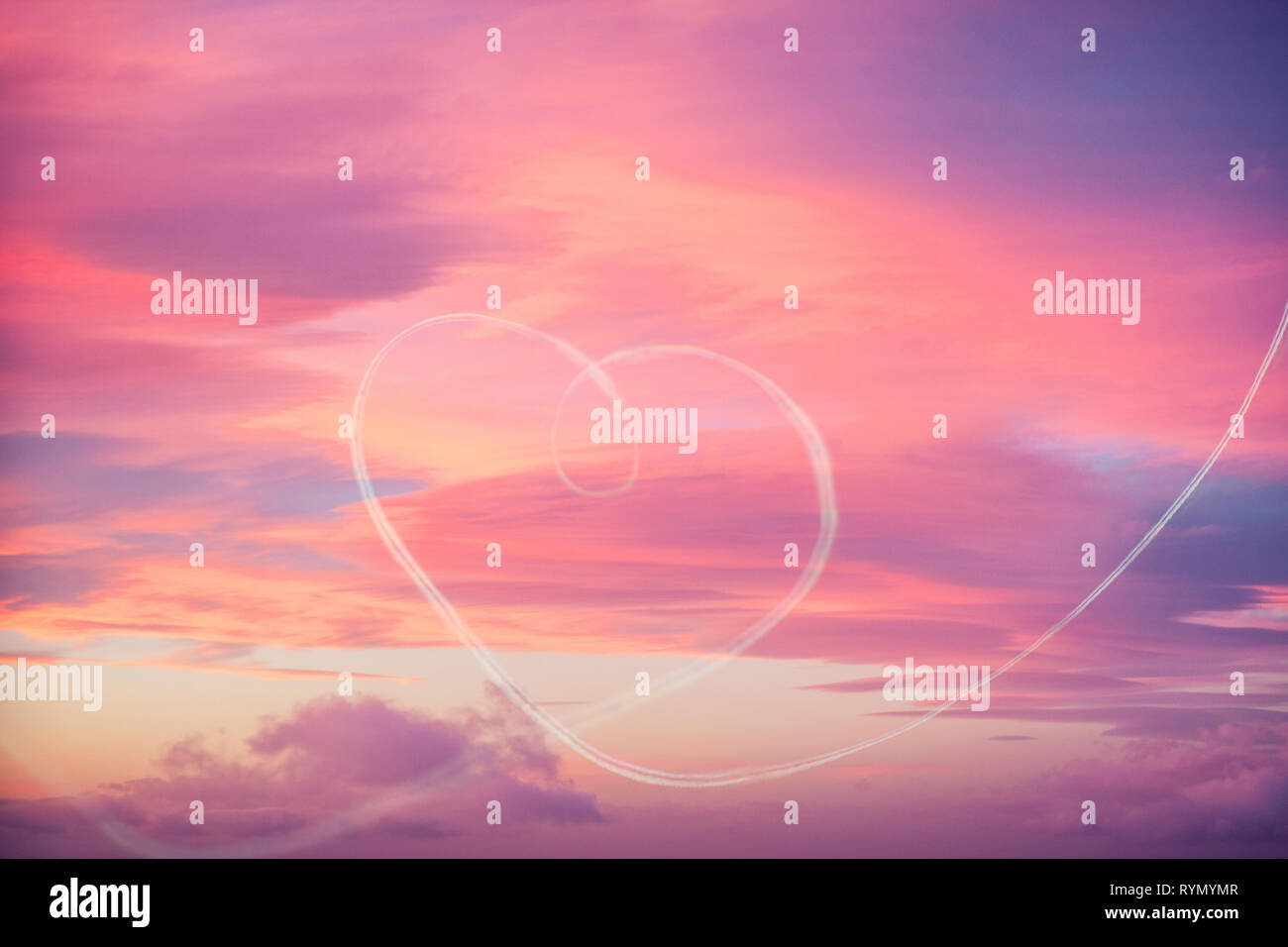 Liebe liegt in der Luft: Ein Herz Form wird auf einen spektakulären Sonnenuntergang Himmel mit Flugzeugen Kurve gezeichnet Stockfoto
