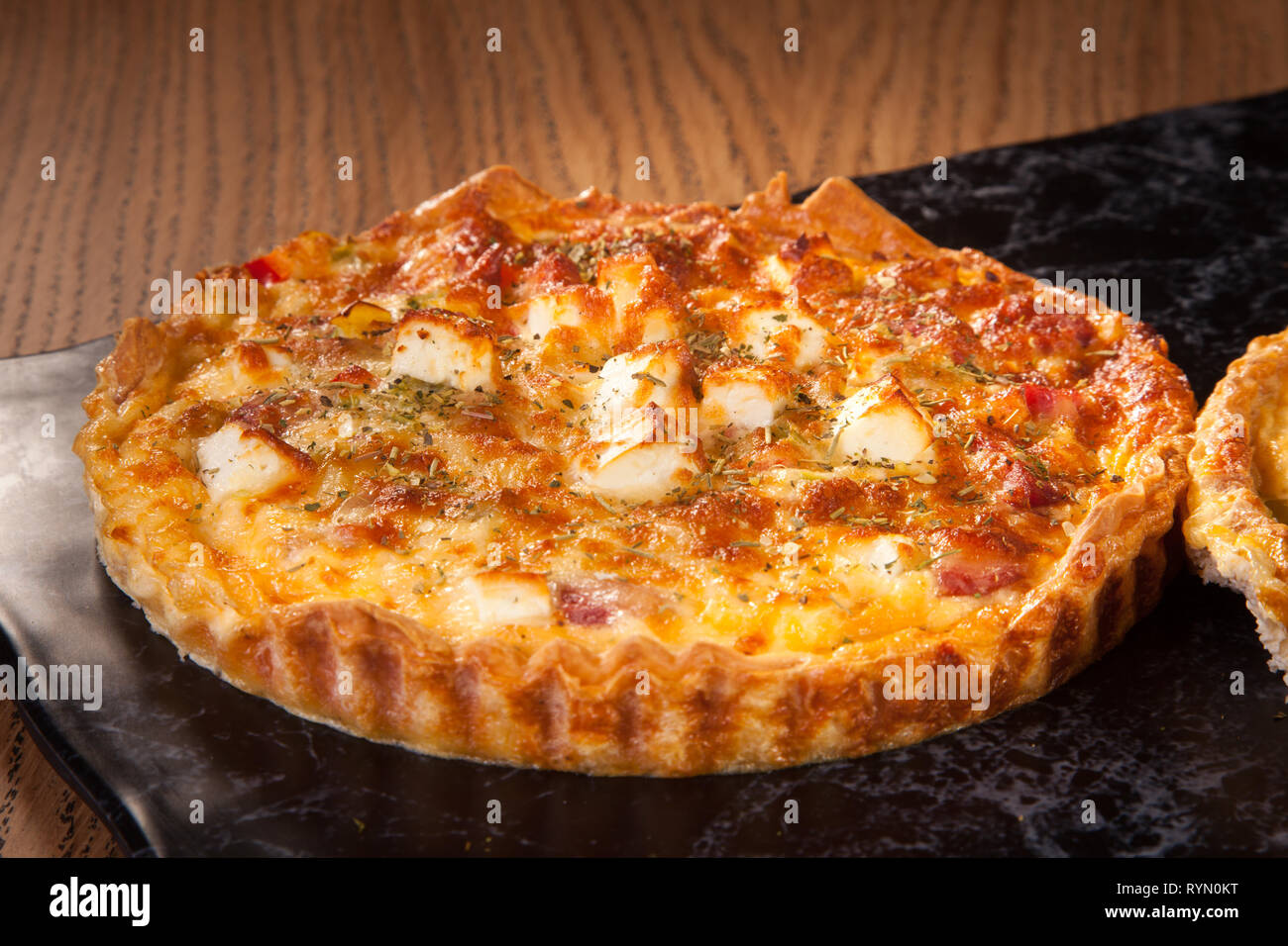Pizza mit Käse serviert auf Holzplatte mit Petersilie Salat grüne Tomatensoße Stockfoto