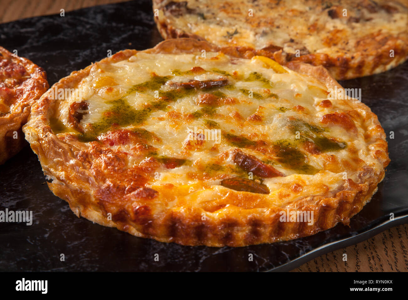 Pizza mit Käse serviert auf Holzplatte mit Petersilie Salat grüne Tomatensoße Stockfoto