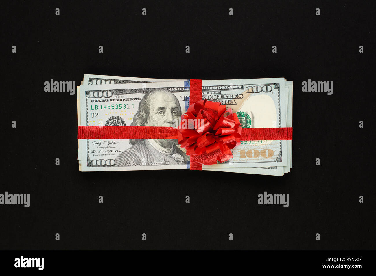 Geld us-Dollar cash Geschenk mit roter Schleife auf schwarzem Hintergrund. Amerikanischer Dollar 100 Banknoten Geschenk gewinn Konzept Stockfoto