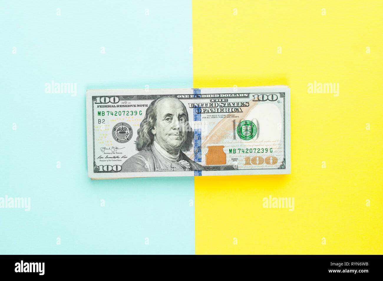 100 US-Dollar bill Geld cash auf blauem und gelbem Hintergrund. Haufen von hundert amerikanische Dollar Banknote Stockfoto