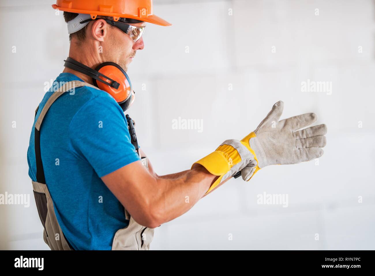 Kaukasische Arbeiter in Helm und Schutzbrille Tragen von Schutzhandschuhen und Vorbereitung auf die Arbeit. Bauindustrie Thema. Stockfoto