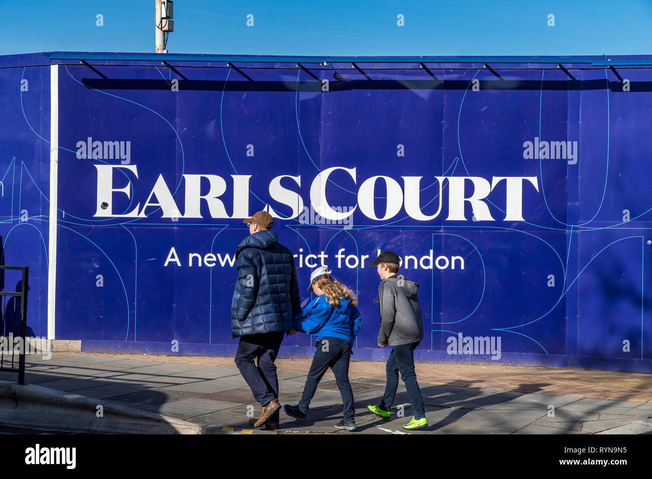 Drei Menschen gehen an einem Purple-Bau-Horten auf der Lillie Road vorbei, der für die neue Earls Court-Entwicklung in London, Großbritannien, wirbt Stockfoto