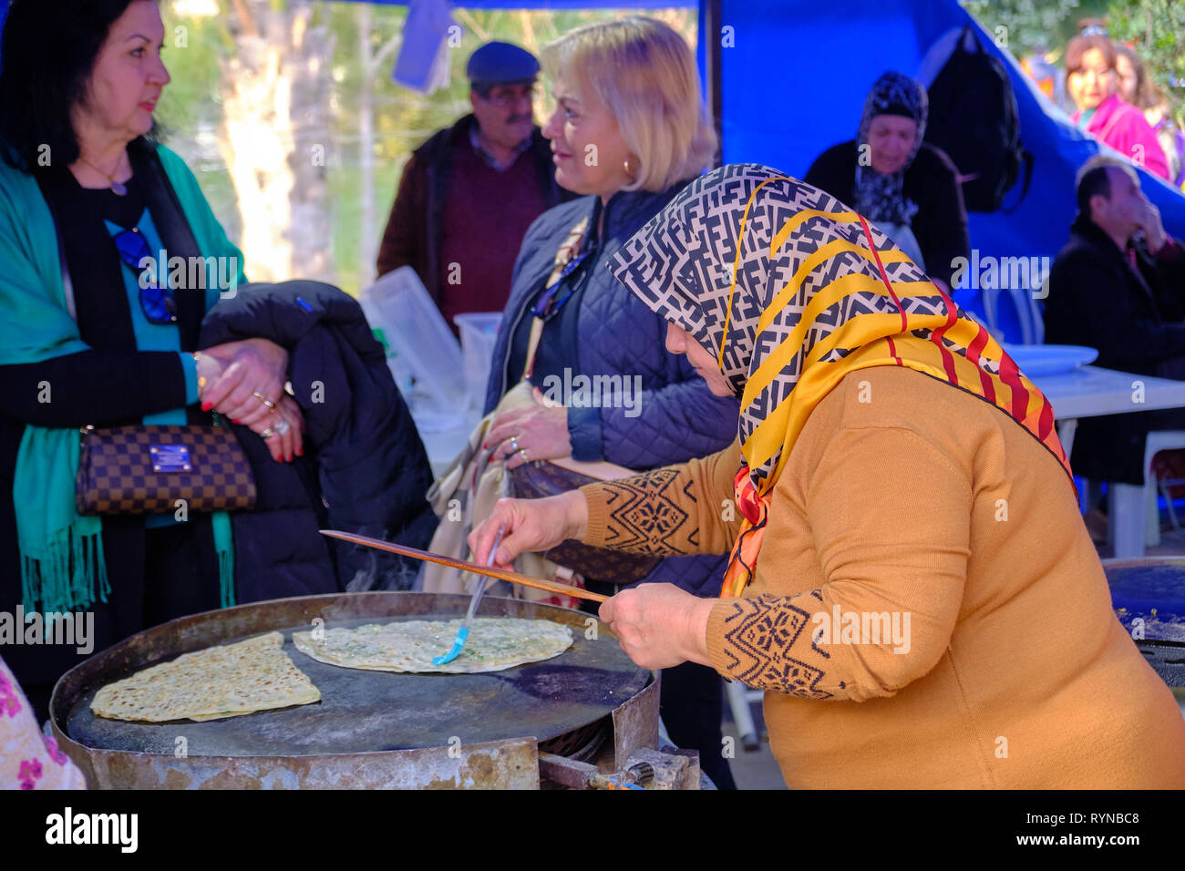 Lokale Frau mit Kopftuch Vorbereitung türkische Pfannkuchen (gözleme) für Kunden, die an einer Messe in Antalya, Türkei Stockfoto