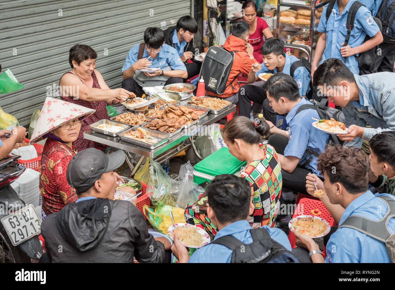 Ho Chi Minh City, Vietnam - Januar 8, 2019: eine Masse von vietnamesischen Studenten in blauen Uniform Essen bei einem Straßenhändler. Stockfoto