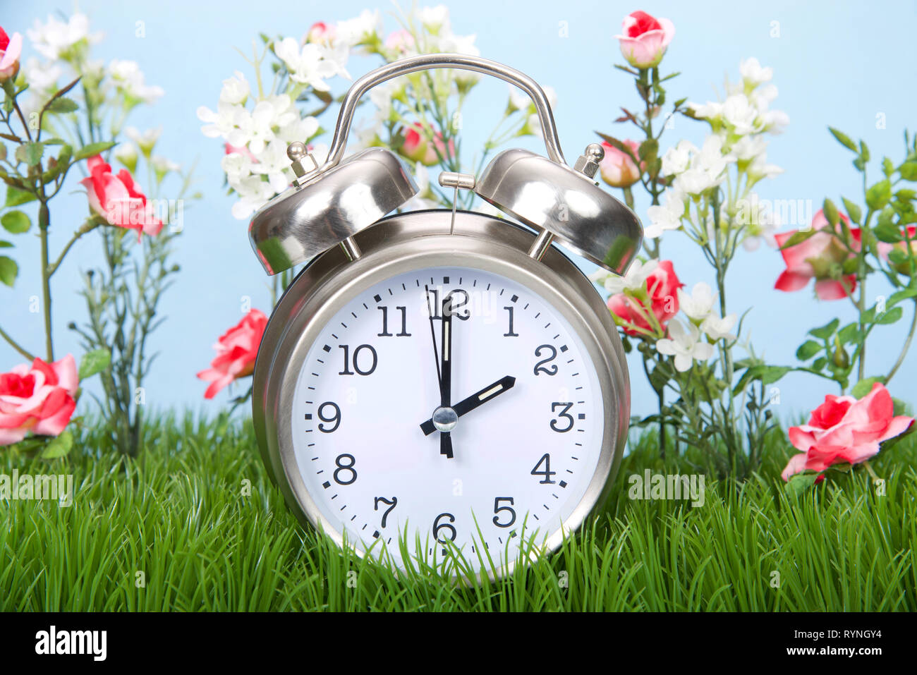 Retro Style Wecker im grünen Gras sitzen mit Blumen, die Sommerzeit Feder nach vorne. Stockfoto