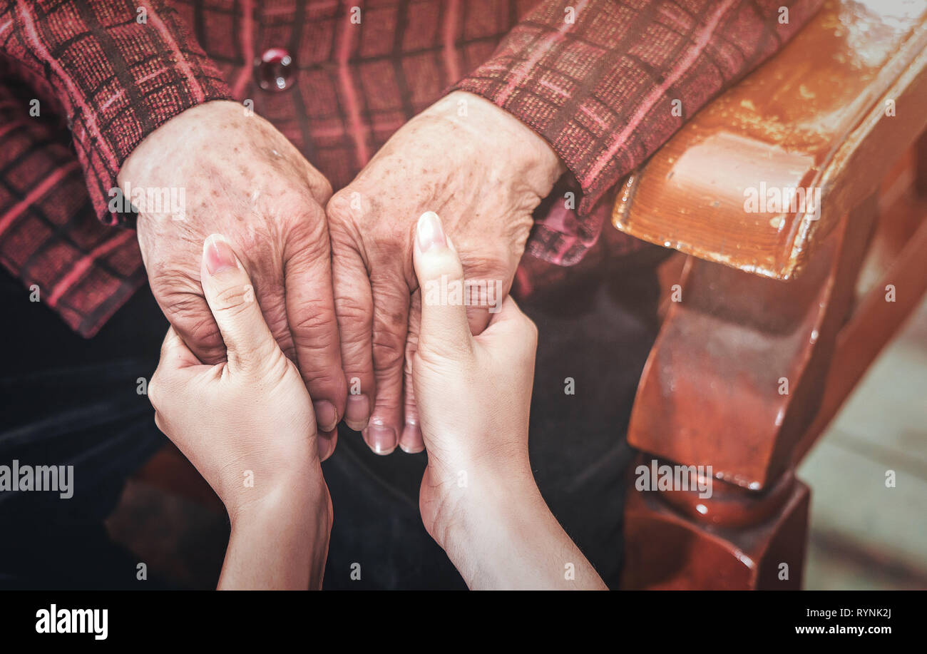 Asien Mädchen im Teenageralter Pflegeperson Holding grandma Hände, helfende Pflege für ältere Menschen leben mit dunklem Hintergrund, Nahaufnahme, Kopieren, 7/8 Stockfoto
