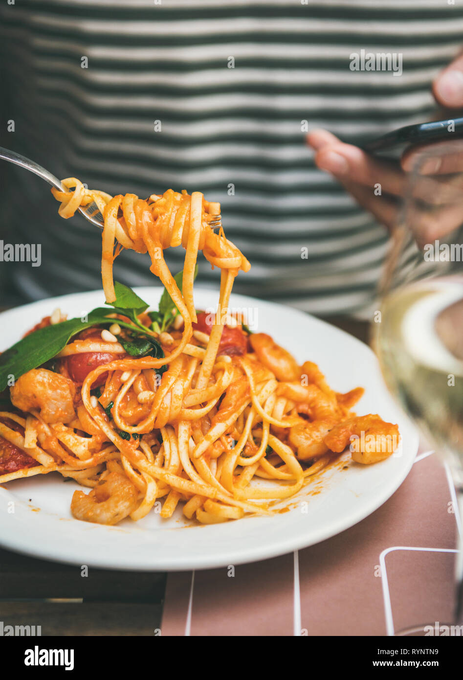 Mann essen Pasta und auf Smartphone Stockfoto