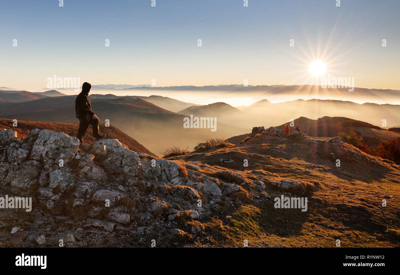Männliche Wanderer auf dem Gipfel des Berges bei Sonnenuntergang Stockfoto