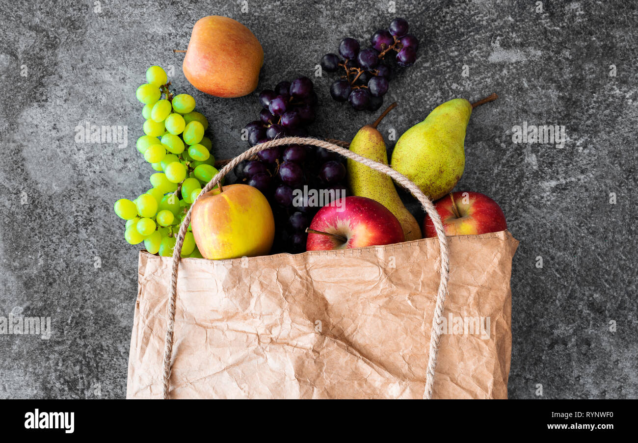 Direkt über Schuss frische organische lokale Früchte in der braunen Papiertüte auf Stein Hintergrund Stockfoto