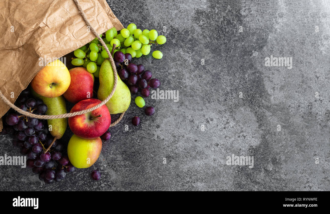 Direkt über Schuss frische organische lokale Früchte in der braunen Papiertüte auf Stein Hintergrund Stockfoto