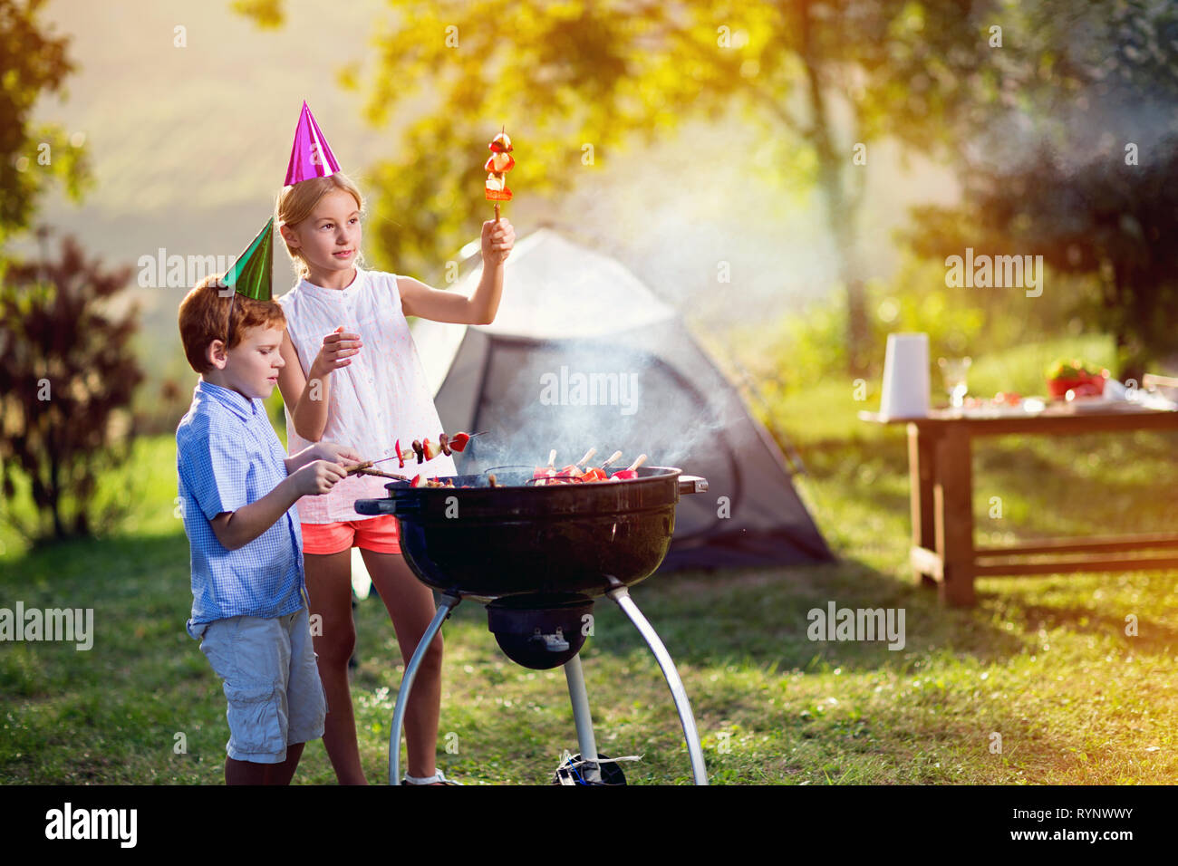 Junge und Mädchen in einem Grillfest auf dem Campingplatz Stockfoto