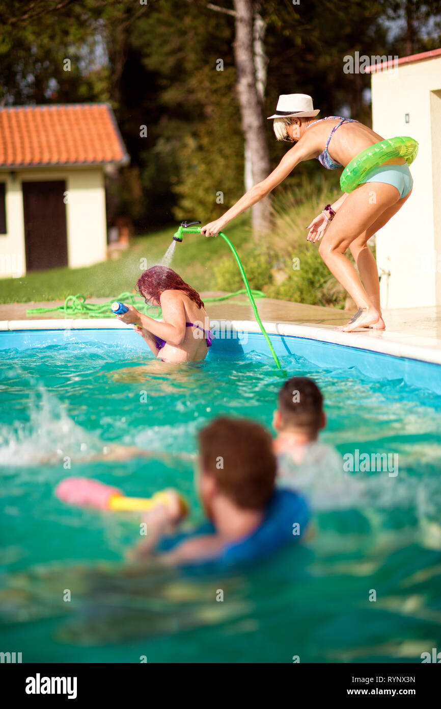 Blonde Mädchen duschen ihre Freundin am Pool und Spaß haben Stockfotografie  - Alamy
