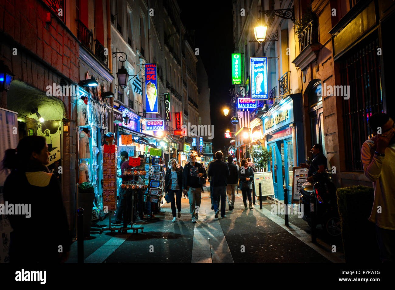 Touristen vorbei an Geschäften und Cafés, wie sie die bunten neon Straßen spät in der Nacht zu Fuß im Quartier Latin von Paris Frankreich Stockfoto