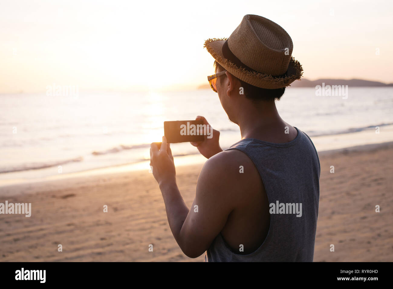 Silhouette zurück von jungen männlichen travel Backpacker mit Hut Fotos von Sommer Strand Landschaft gegen Sonnenuntergang - Reise Bild moment Konzept erfasst Stockfoto