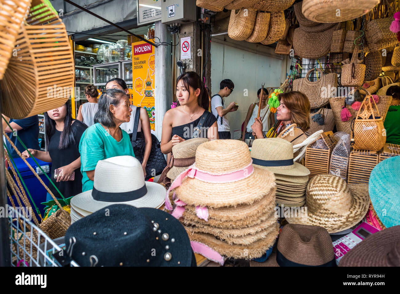 Bangkok, Thailand - 13. Mai 2018: Drei Frauen miteinander reden hinter einer Ladentheke mit Hüten und Korbwaren Taschen bei Chatuchak Weekend Market gefüllt. Stockfoto