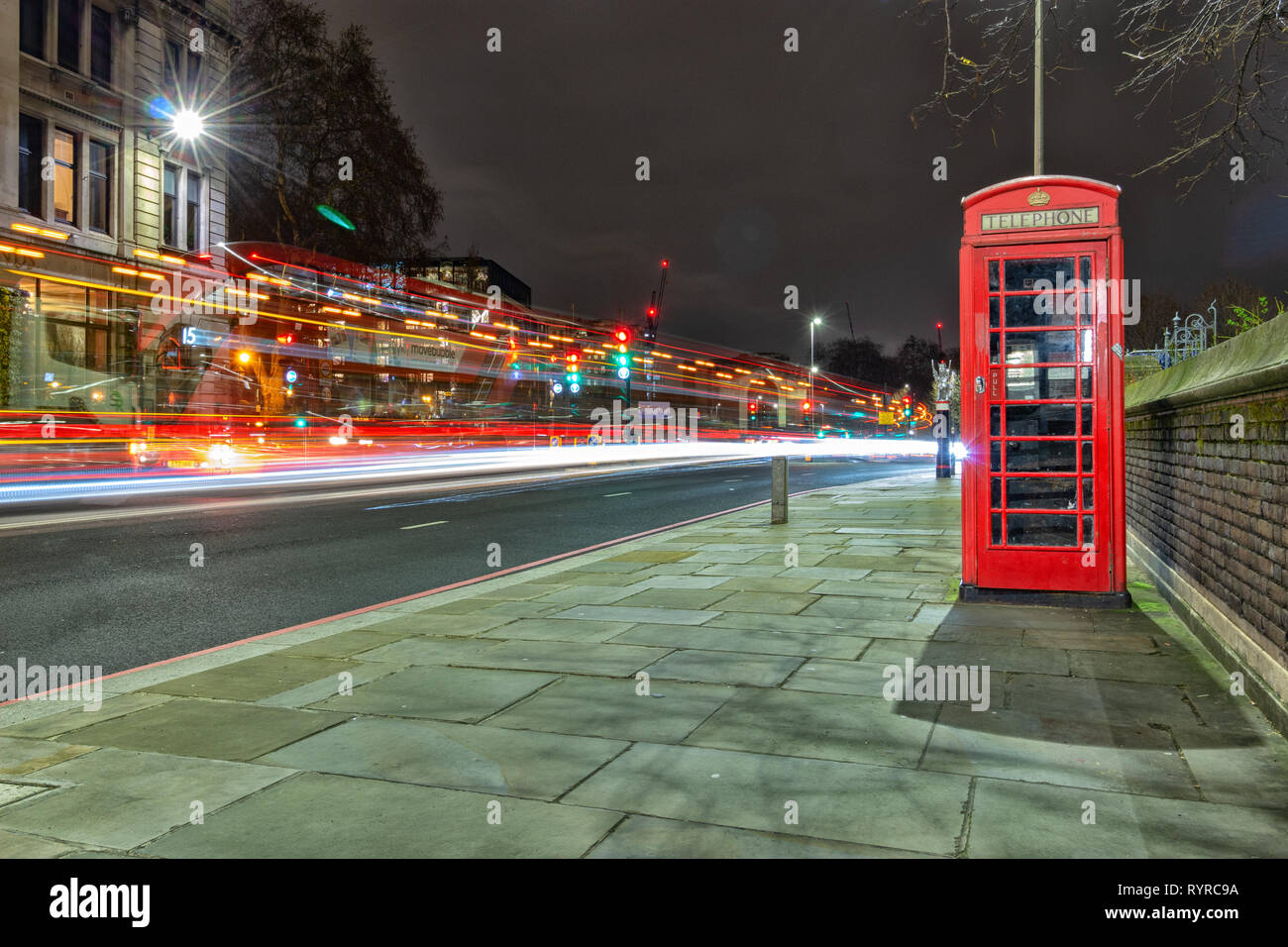 London, England, 14. März 2019. Eine berühmte rote Telefonzelle in der Stadt neben einer viel befahrenen Straße mit leichten Wanderwegen bei Nacht Stockfoto