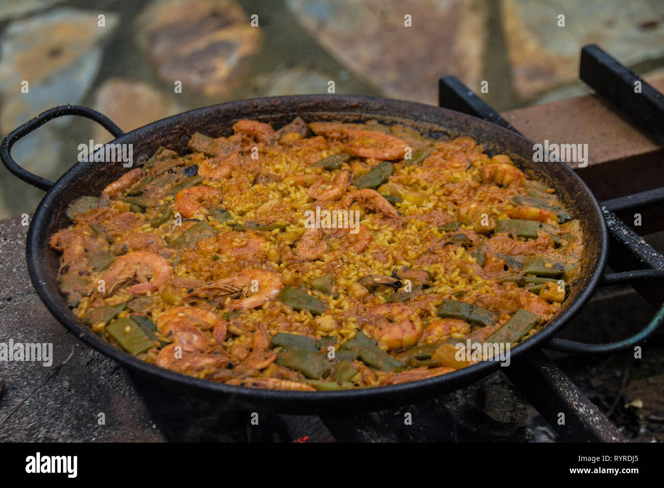 Spanische Paella auf natürliche Feuer und Kohle log in traditionellen Kamin gekocht. Stockfoto