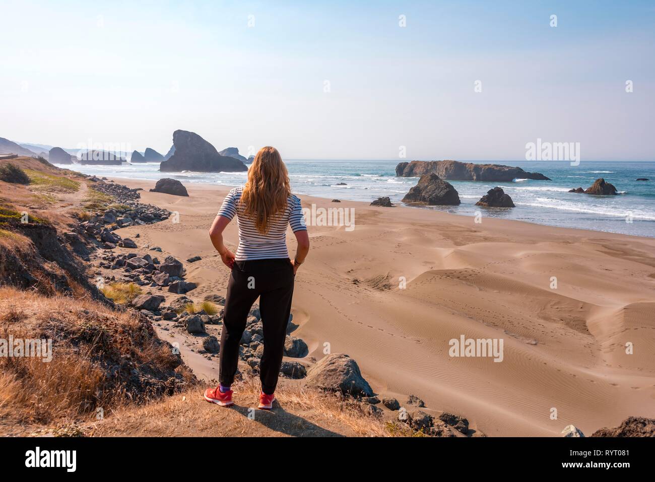 Junge Frau über Sandstrand suchen Küste mit schroffen Felsen, Myers Creek Strand Sicht, Oregon USA Stockfoto