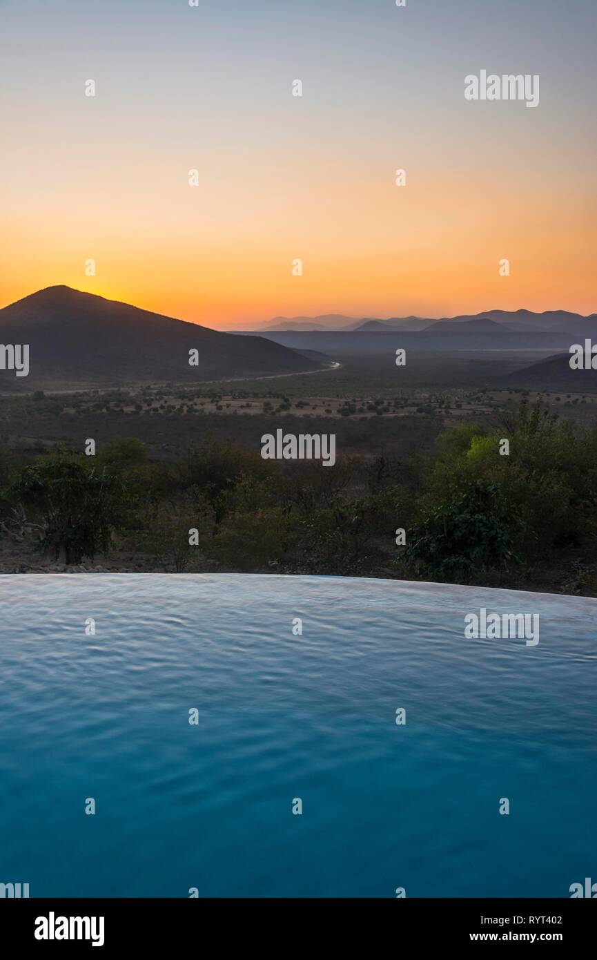 Swimmingpool über schönen Ausblick mit Blick auf die Berge bei Sonnenuntergang, Ovapu, Kaokoveld, Namibia Stockfoto