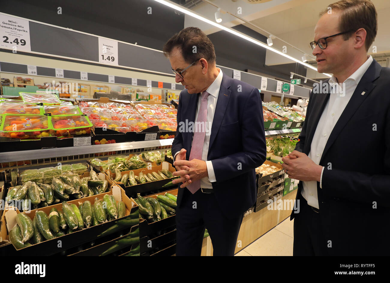 Berlin, Deutschland. 15 Mär, 2019. Gerd Müller (CSU), Bundesminister für wirtschaftliche Zusammenarbeit und Entwicklung, ist über den fairen Einkauf in einen LIDL Supermarkt in Berlin informiert und wird von Matthias Oppitz (r), CEO von Lidl Deutschland, auf eine gemeinsame Supermarkt Tour begleitet und fragt, warum organische Gurken in Plastikfolie eingewickelt zu sein haben. Quelle: Wolfgang Kumm/dpa/Alamy leben Nachrichten Stockfoto