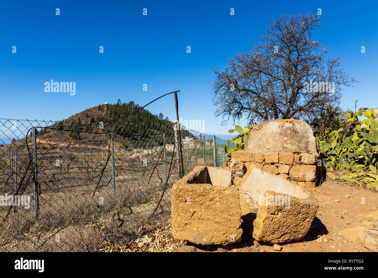 Eine gebrochene Stein Schiff auf dem Boden vor einem alten Ofen im Garten eines Bauernhauses in Las Fuentes, Guia de Isora, Teneriffa, Kanarische Inseln, Spai Stockfoto