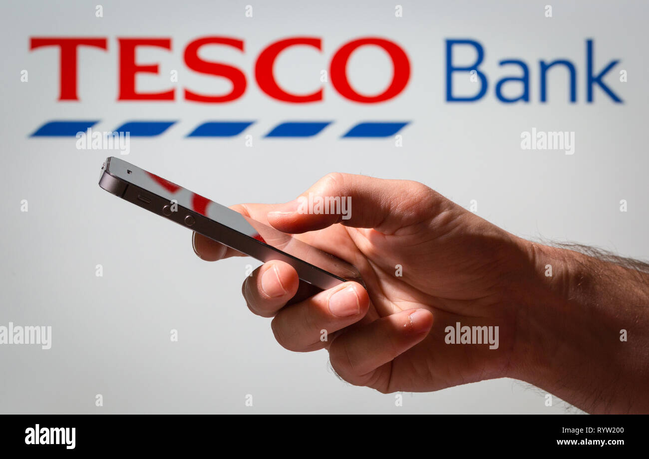 Ein Mann mit Tesco Bank online Banking auf seinem Mobiltelefon Stockfoto