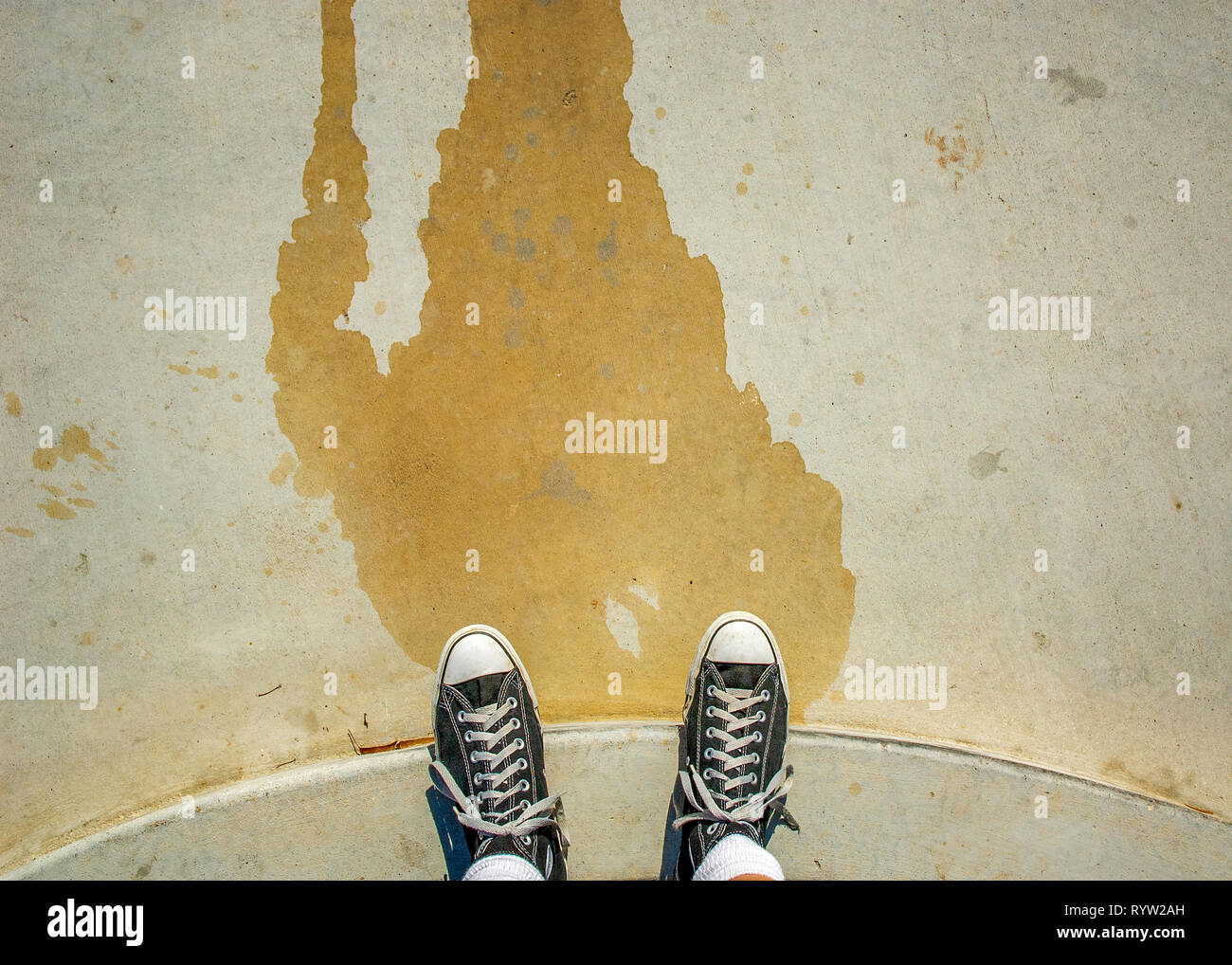 POV von schwarzen Sneakers auf Zement bändigen. Stockfoto