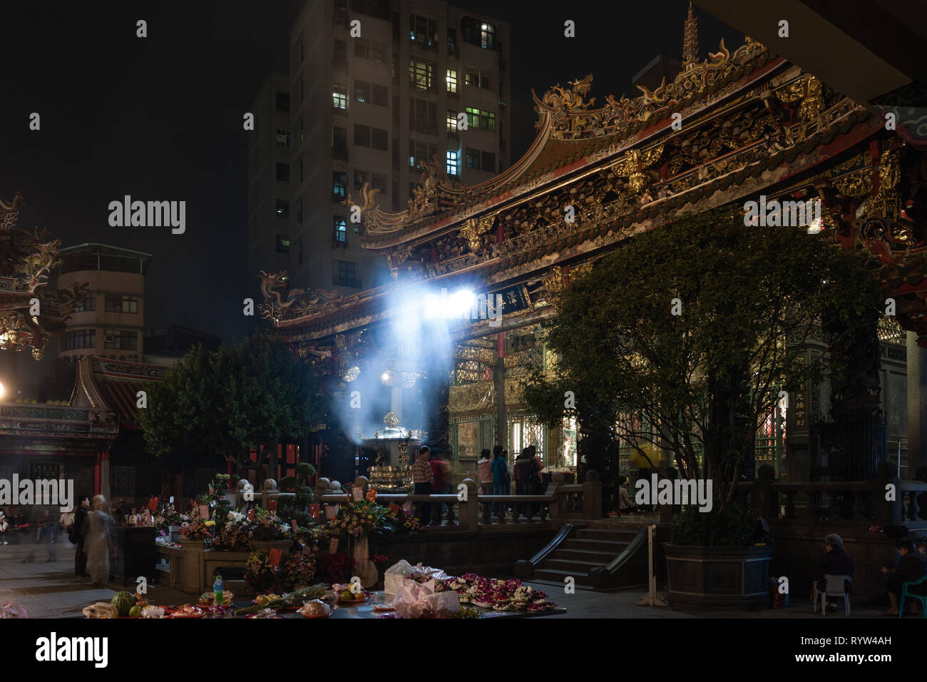Lungshan Tempel, historischen buddhistischen und taoistischen Tempel, Rauch von brennenden Räucherstäbchen und Anbeter versammeln sich um den Altar, in der Nacht, Taipei, Taiwan Stockfoto